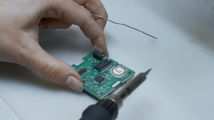 Poster - Young man repairing computer components in service center. Creative. Close up of soldering the chip.