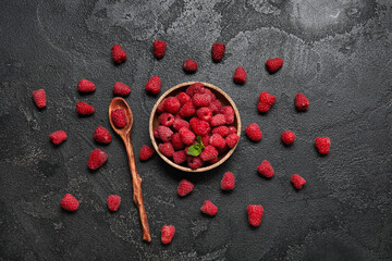 Wooden bowl with fresh raspberry and spoon on dark background