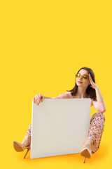 Poster - Stylish young woman with blank poster on yellow background