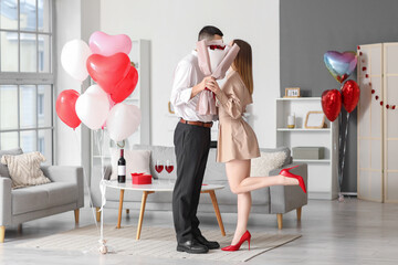 Poster - Beautiful young couple with bouquet of flowers and heart-shaped balloons celebrating Valentine's Day at home