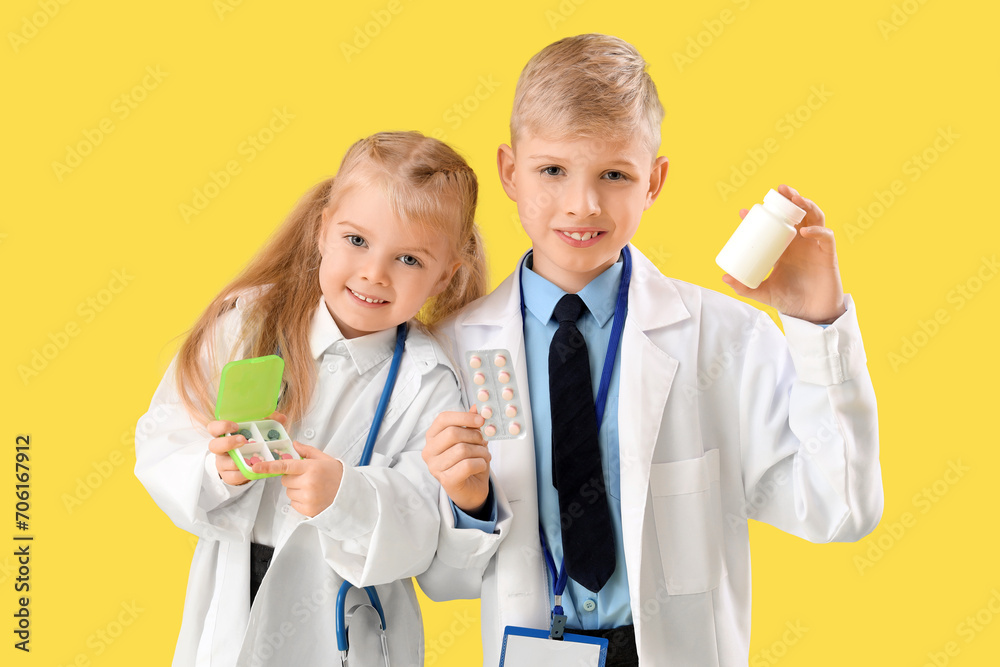 Cute little doctors with pills on yellow background. Opposite Day celebration