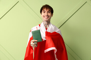 Canvas Print - Handsome young man with flag of Canada and passport on green background. Immigration concept