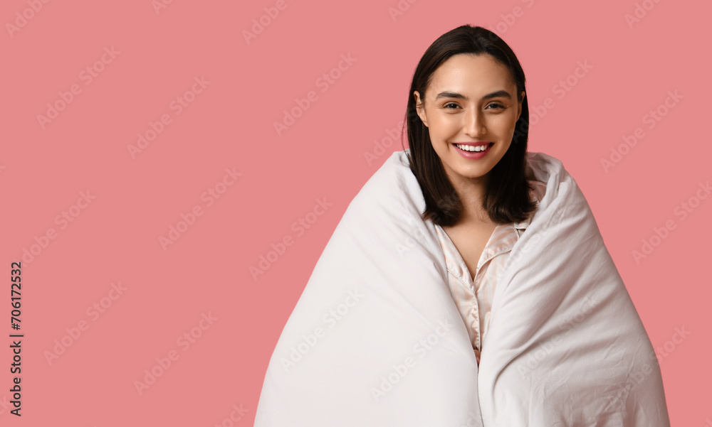 Pretty young woman with blanket on pink background
