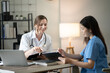 © aekachai - Female doctor sitting at work looking at the history of patients in the clinic or in the hospital