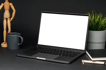 Canvas Print - Open laptop with wooden mannequin on table against black background