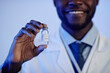 Cropped shot of happy African American scientist showing glass medical ampoule vial with COVID-19 vaccine