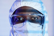 Extreme close up shot of Black man laboratory technician in hazmat suit and protective glasses looking at camera
