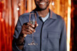 Cropped shot of smiling Black man at club party with focus on glass of mouthfeel champagne in hand