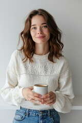 Poster - A woman is holding a cup of coffee. This image can be used to depict relaxation, morning routines, or enjoying a warm beverage