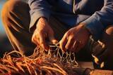 Fototapeta  - An elderly fisherman expertly mending a fishing net with his weathered hands.