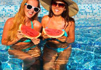 Two sexy women with dark hair eating watermelon