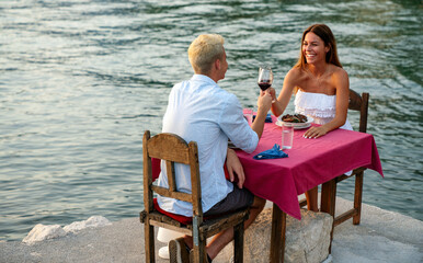 Wall Mural - People, vacation, love and romance concept. Young couple enjoying a romantic dinner on beach.