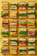 A variety of sandwiches with different fillings, such as meats, cheeses, and vegetables, carefully aligned against a vibrant yellow backdrop.