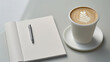 © BONI - Taza de café  blanca y cuaderno en blanco de notas para escribir sobre una mesa en la oficina.