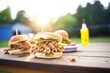 multiple sloppy joes on a picnic table, outdoor light