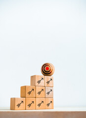 Poster - Big target icon on wooden sphere on top of cube blocks bar graph chart steps with arrows symbol on desk, white vertical background. Investment, income, revenue, profit goal, business growth concepts.