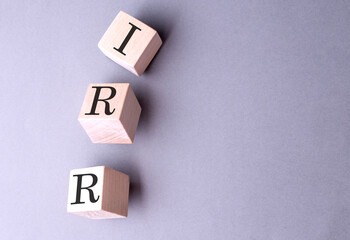 Poster - Word IRR on wooden block on the grey background