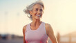 A mature woman in athletic wear exudes vitality and joy as she exercises outdoors, her hair swept back by the breeze, showcasing active aging and a commitment to health and fitness.