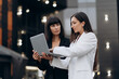 © MZaitsev - Meeting of two business women. Two young women dressed in business suits are discussing a project on a city street.