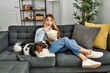 © Krakenimages.com - Young caucasian woman surprised watching movie sitting on sofa with dog at home