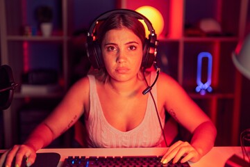 Wall Mural - Young blonde woman playing video games wearing headphones depressed and worry for distress, crying angry and afraid. sad expression.