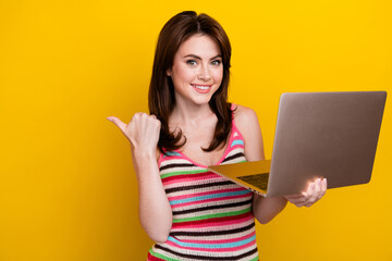 Poster - Photo of good mood girl wear striped tank hold laptop indicating at promo discount empty space isolated on yellow color background