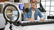 © Krakenimages.com - Handsome middle-aged hispanic man playing keyboard in well-equipped home music studio with recording equipment.
