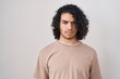 Hispanic man with curly hair standing over white background skeptic and nervous, frowning upset because of problem. negative person.