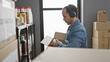 © Krakenimages.com - Hispanic man with beard wearing headphones checks inventory in warehouse full of boxes and donations.