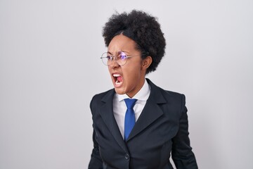 Poster - Beautiful african woman with curly hair wearing business jacket and glasses angry and mad screaming frustrated and furious, shouting with anger. rage and aggressive concept.