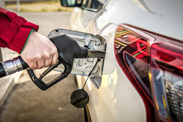 Car fueling at gas station. Refuel fill up with petrol gasoline. Petrol pump filling fuel nozzle in fuel tank of car at gas station