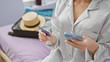 © Krakenimages.com - Beautiful young hispanic woman sitting in hotel room, using smartphone and holding credit card, surrounded by suitcase packed for vacation