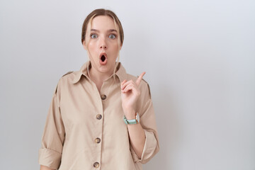 Wall Mural - Young caucasian woman wearing casual shirt surprised pointing with finger to the side, open mouth amazed expression.