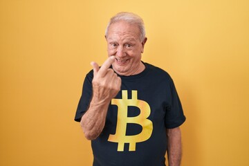 Wall Mural - Senior man with grey hair wearing bitcoin t shirt beckoning come here gesture with hand inviting welcoming happy and smiling