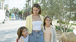 © Krakenimages.com - A smiling young woman with two girls on a sunny city street lined with trees