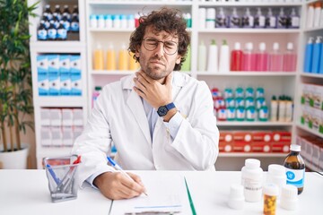 Wall Mural - Hispanic young man working at pharmacy drugstore touching painful neck, sore throat for flu, clod and infection