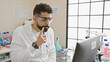 © Krakenimages.com - Thoughtful hispanic man wearing glasses and lab coat contemplating in a science laboratory.