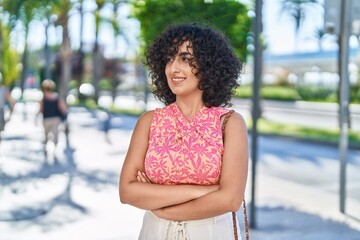 Wall Mural - Young middle eastern woman standing with arms crossed gesture at street