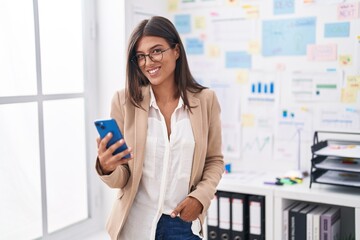 Canvas Print - Young beautiful hispanic woman business worker smiling confident using smartphone at office