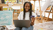 © Krakenimages.com - Smiling woman with credit card shopping online on laptop in art studio