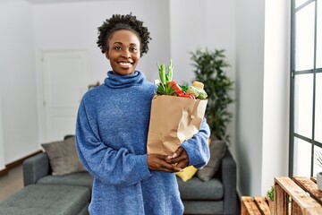 Sticker - African american woman smiling confident holding groceries bag at home