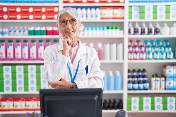 Sticker - Middle age woman with tattoos working at pharmacy drugstore with hand on chin thinking about question, pensive expression. smiling and thoughtful face. doubt concept.