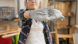 © Krakenimages.com - Beautiful grey-haired middle age woman carpenter, stretching arms, wearing gloves at her indoor carpentry workshop, mastering her profession amidst wood and lumber