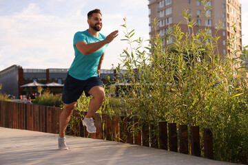 Poster - Smiling man running outdoors on sunny day. Space for text