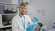 © Krakenimages.com - Caucasian man with a beard in a laboratory holding a beaker with blue liquid, conveying a sense of expertise.