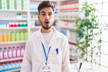 Canvas Print - Young hispanic man with tattoos working at pharmacy drugstore scared and amazed with open mouth for surprise, disbelief face