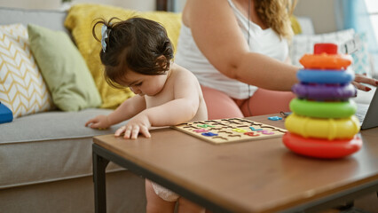 Loving mother and daughter cherish family time, sitting on the sofa playing maths game, bonding over technology at home