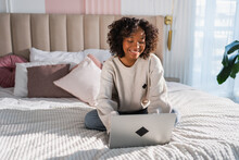 African American girl using laptop in bed at home office typing chatting reading writing email. Young black woman having virtual meeting online chat video call conference. Work learning from home