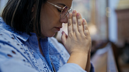 Wall Mural - Young beautiful hispanic woman praying on a church bench at St. Karl BorromÃ¤us church