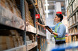 © KANGWANS - Warehouse worker in security uniform with tablet computer looking at merchandise in large warehouse Logistics and export business Logistics distribution center.